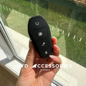 Hand holding a car key fob with visible brand 'BYD Accessories Australia' in front of a window.