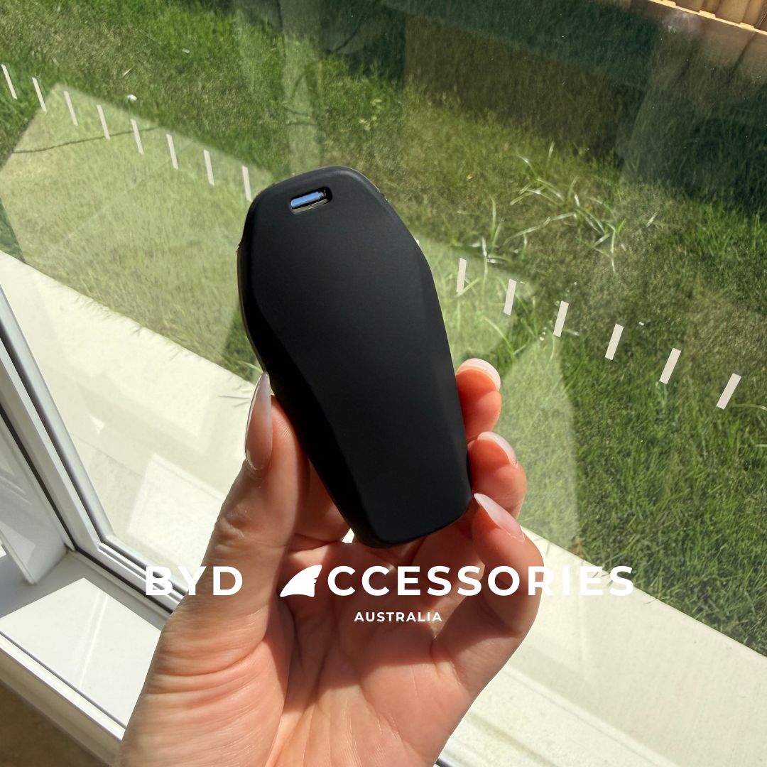 Hand holding a black KEY case with grass and window in the background, featuring 'BYD Accessories Australia' branding.