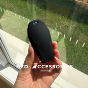 Hand holding a black KEY case with grass and window in the background, featuring 'BYD Accessories Australia' branding.