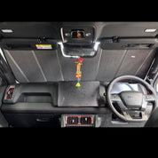 Car interior with dashboard and steering wheel, featuring a decorative item hanging from the rearview mirror.